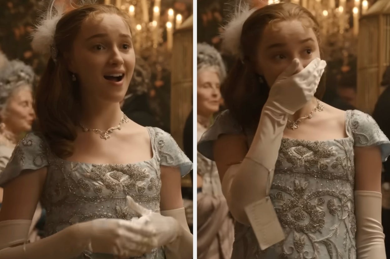 A woman in an elegant, embroidered gown and long gloves covers her mouth in surprise at a formal event