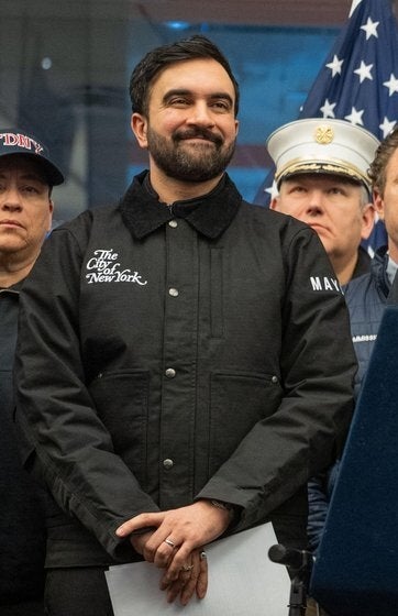 Bildet viser en gruppe tjenestemenn og respondere på en pressebriefing, med en mann som taler ved et podium med et offisielt segl