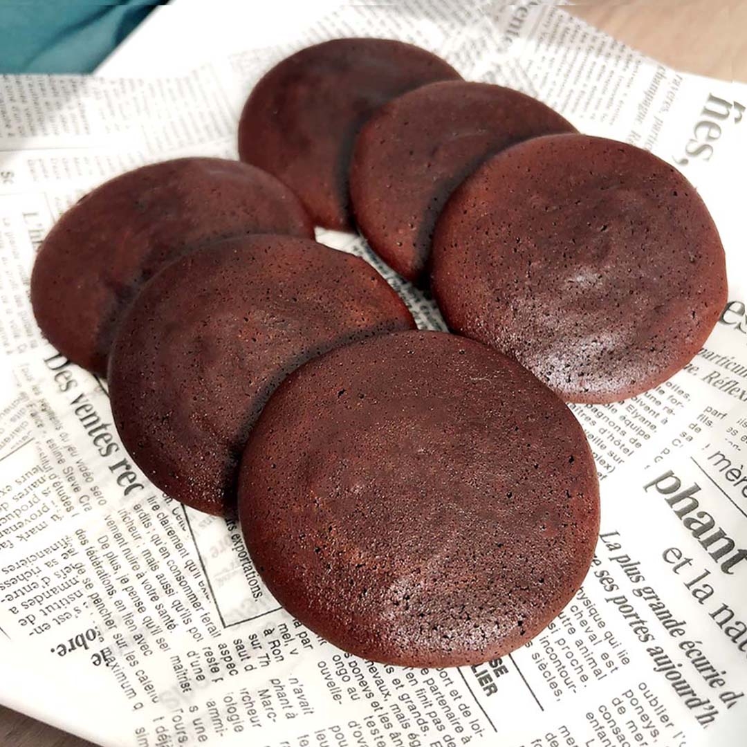 新聞紙の上に並んだ6枚のチョコレートクッキー。