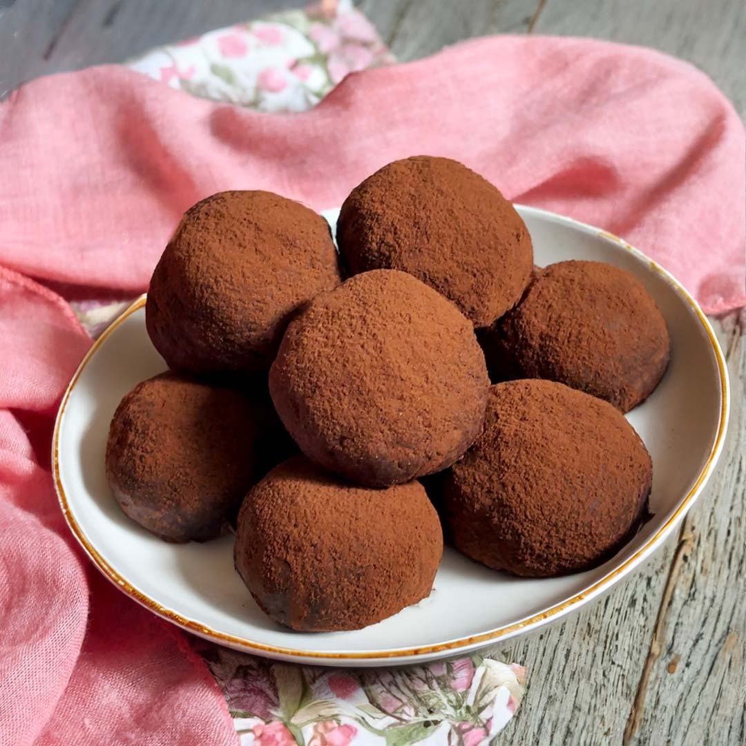 皿に載ったチョコレートトリュフが積まれている。背景にピンクの布がある。