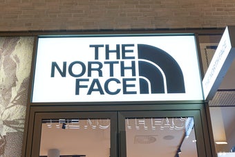 店舗外観。ザ・ノース・フェイスのロゴが店舗入口上部に表示され、店内にはアウトドア用品や衣類が陳列されている。