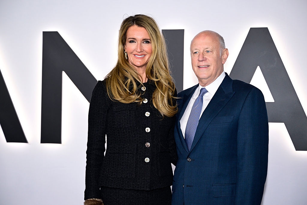 To personer poserer på en rød løper. Kvinnen har på seg en stilig knappejakke, og mannen er i dress og slips