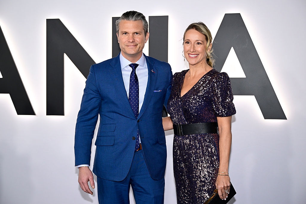 To personer som poserer på et arrangement; den ene i blå dress og slips, den andre i en glitrende kjole med svart belte