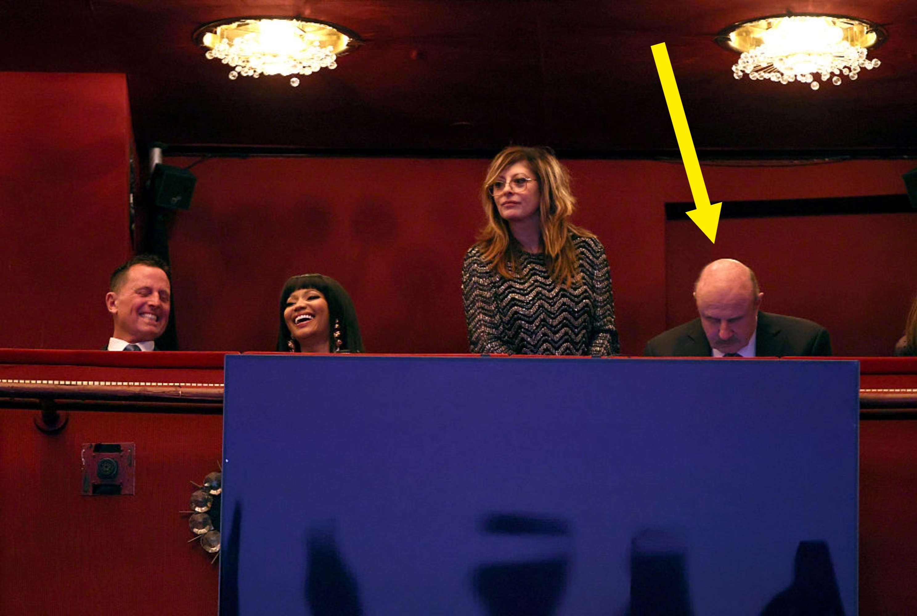 En gruppe mennesker i en teaterboks, med to sittende og to stående, smilende og i samtale