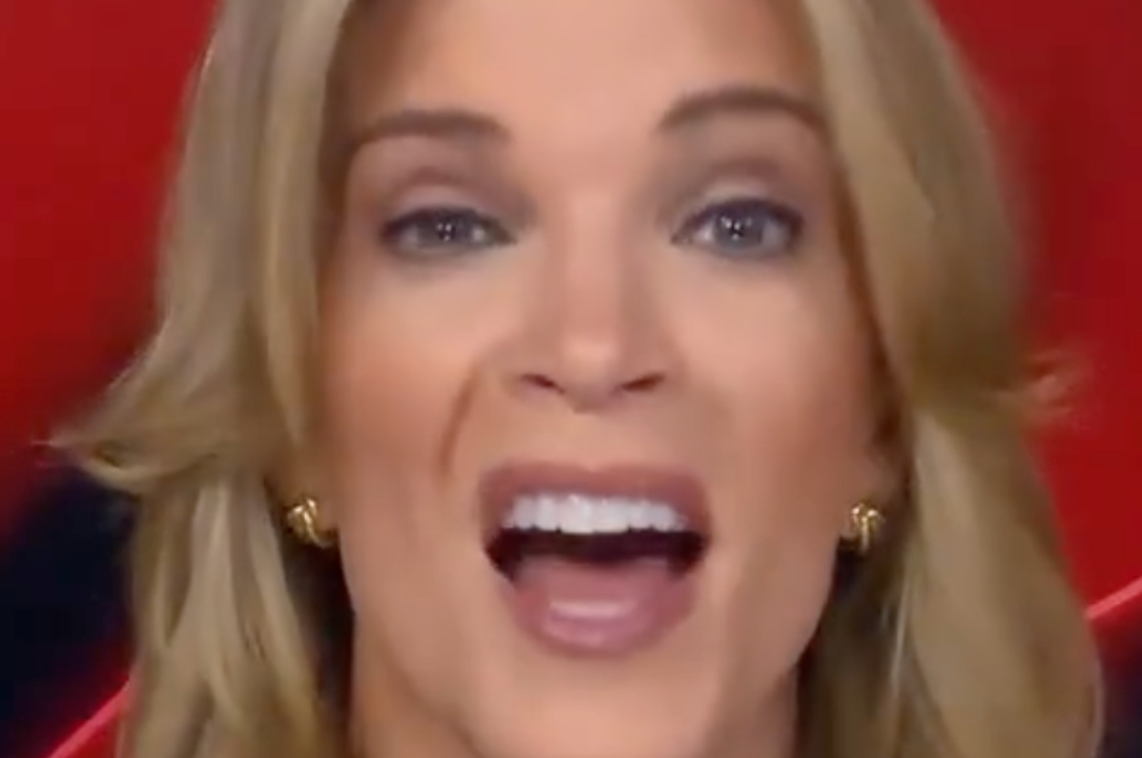 Person speaking energetically, wearing earrings, with blond hair; background appears to be indoors