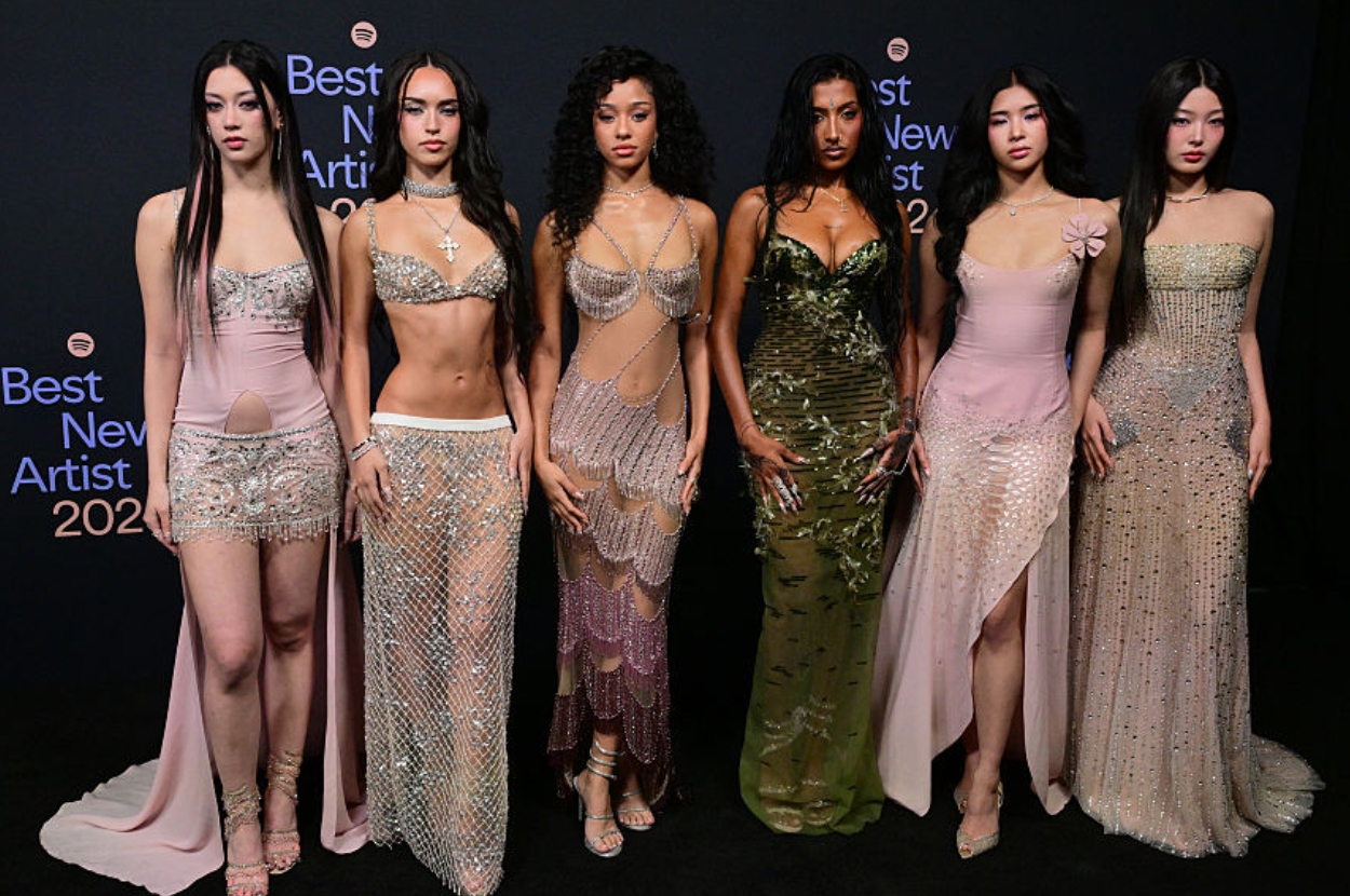 Six women on a red carpet, each wearing unique, stylish gowns with intricate designs and embellishments, posing for "Best New Artist 2023."