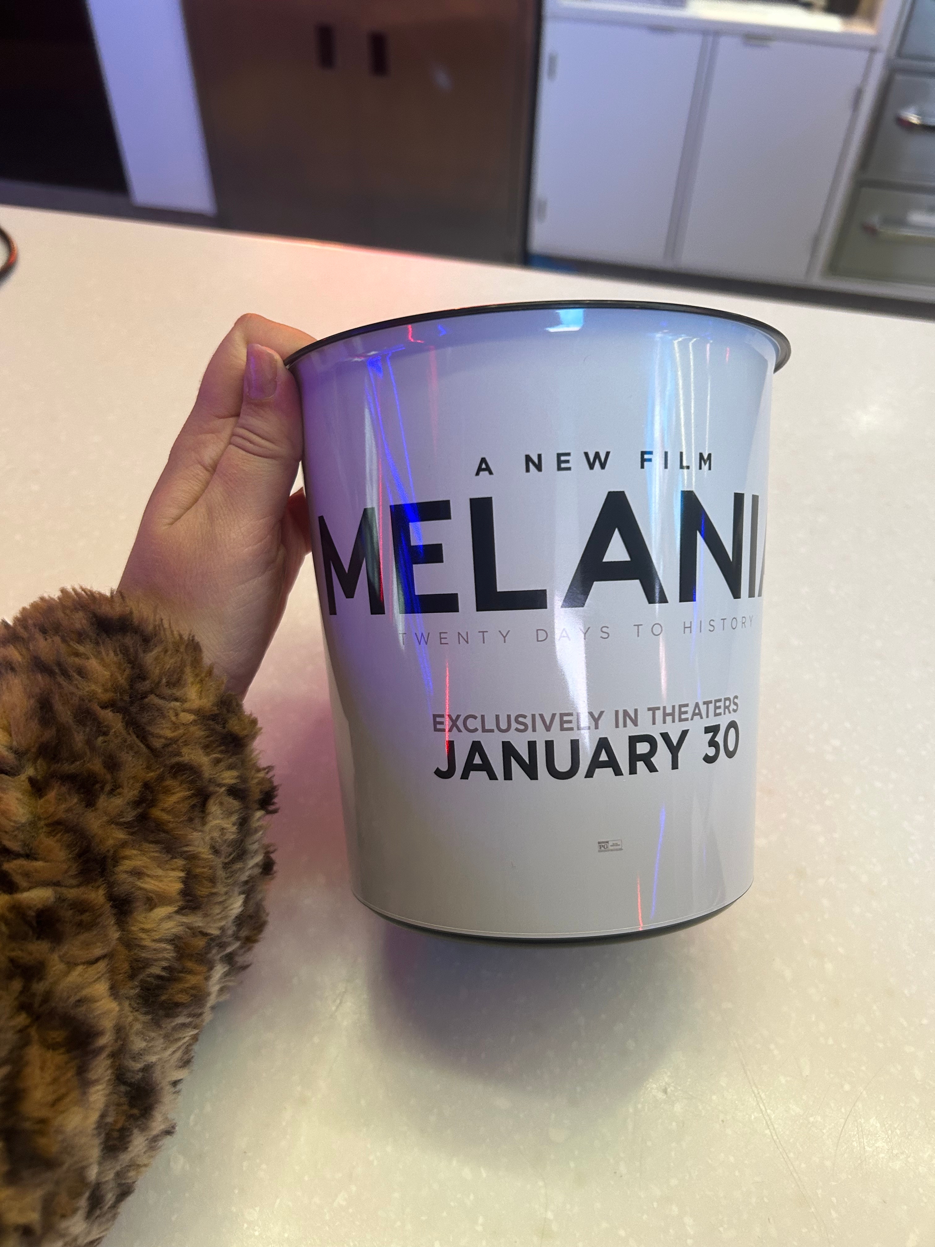 En hånd som holder en popcornbøtte som promoterer filmen «Melani»; med utgivelsesdato 30. januar