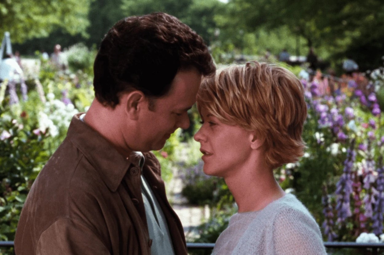 A woman and man gaze at each other tenderly in a garden setting