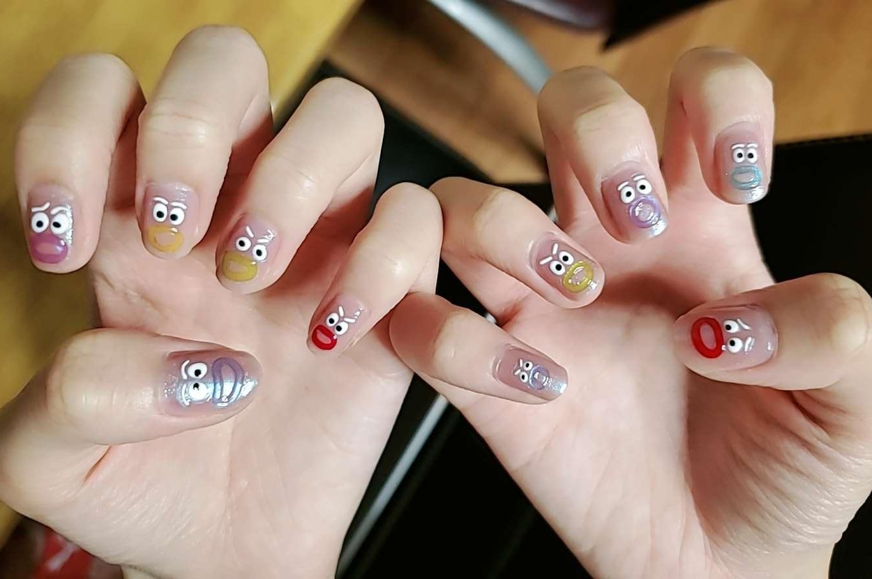 Hands with Muppet-themed nail art, each featuring different character faces with expressive eyes and mouths