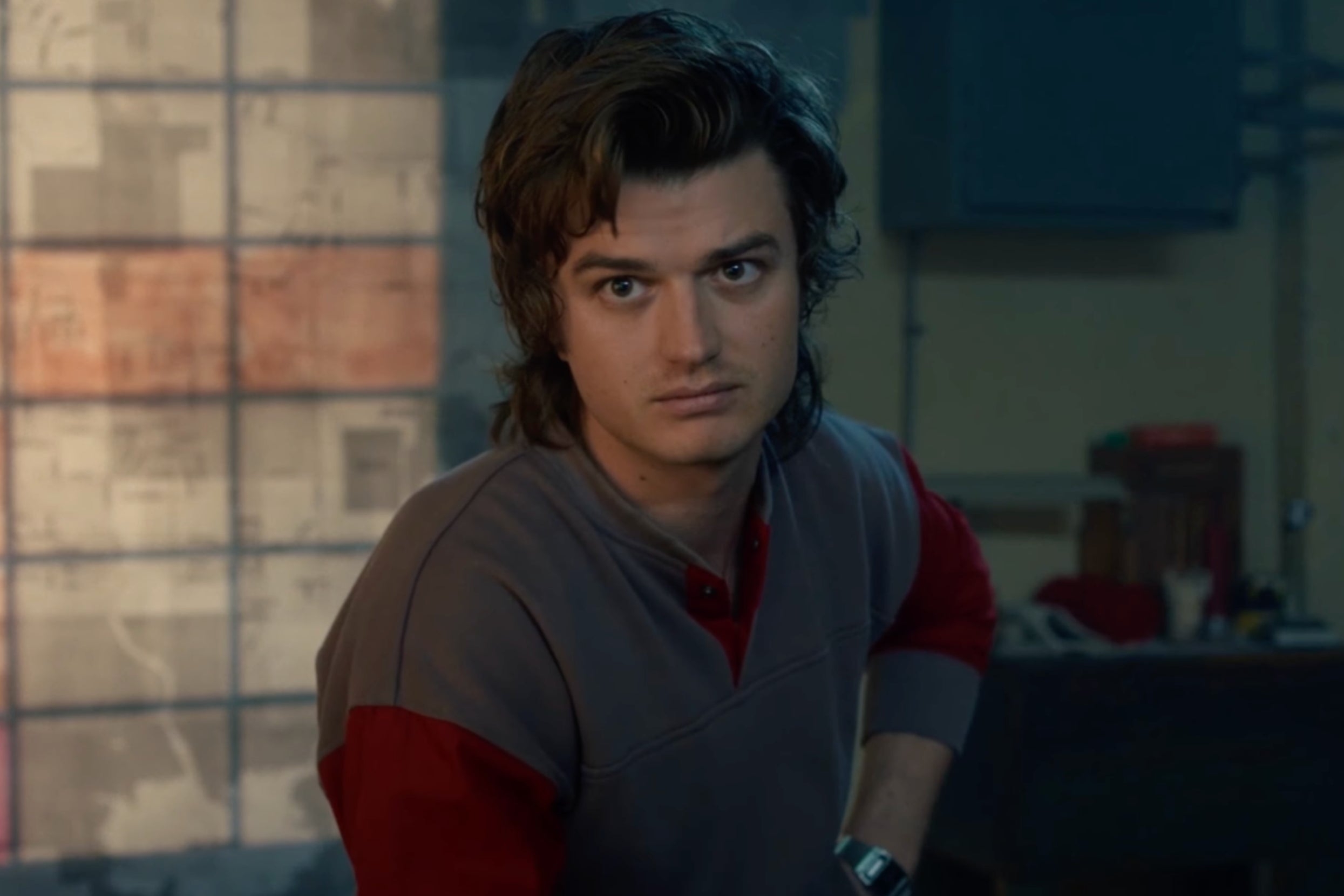 A idiosyncratic   with medium-length hairsbreadth  wearing a casual long-sleeve garment  stands indoors, looking straight  astatine  the camera