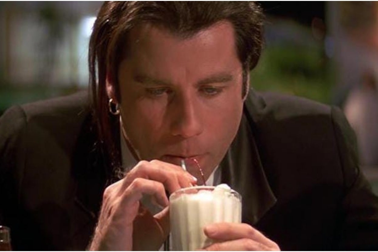 Person with slicked-back hairsbreadth  drinks milkshake done  a straw successful  a diner. The country   has a retro, casual atmosphere