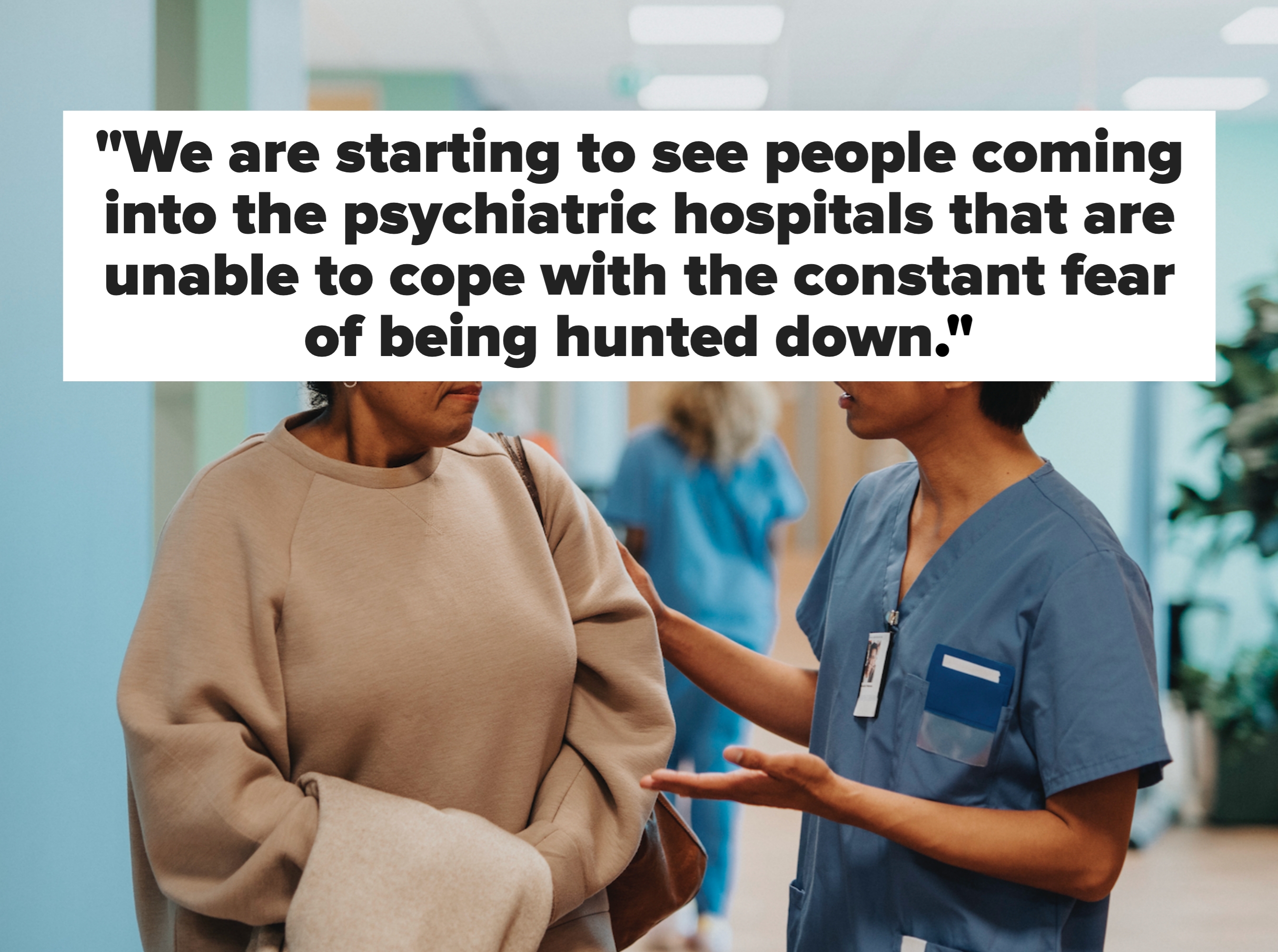 Helsepersonell i scrubs snakker med en bekymret kvinne som holder en frakk i en sykehusgang