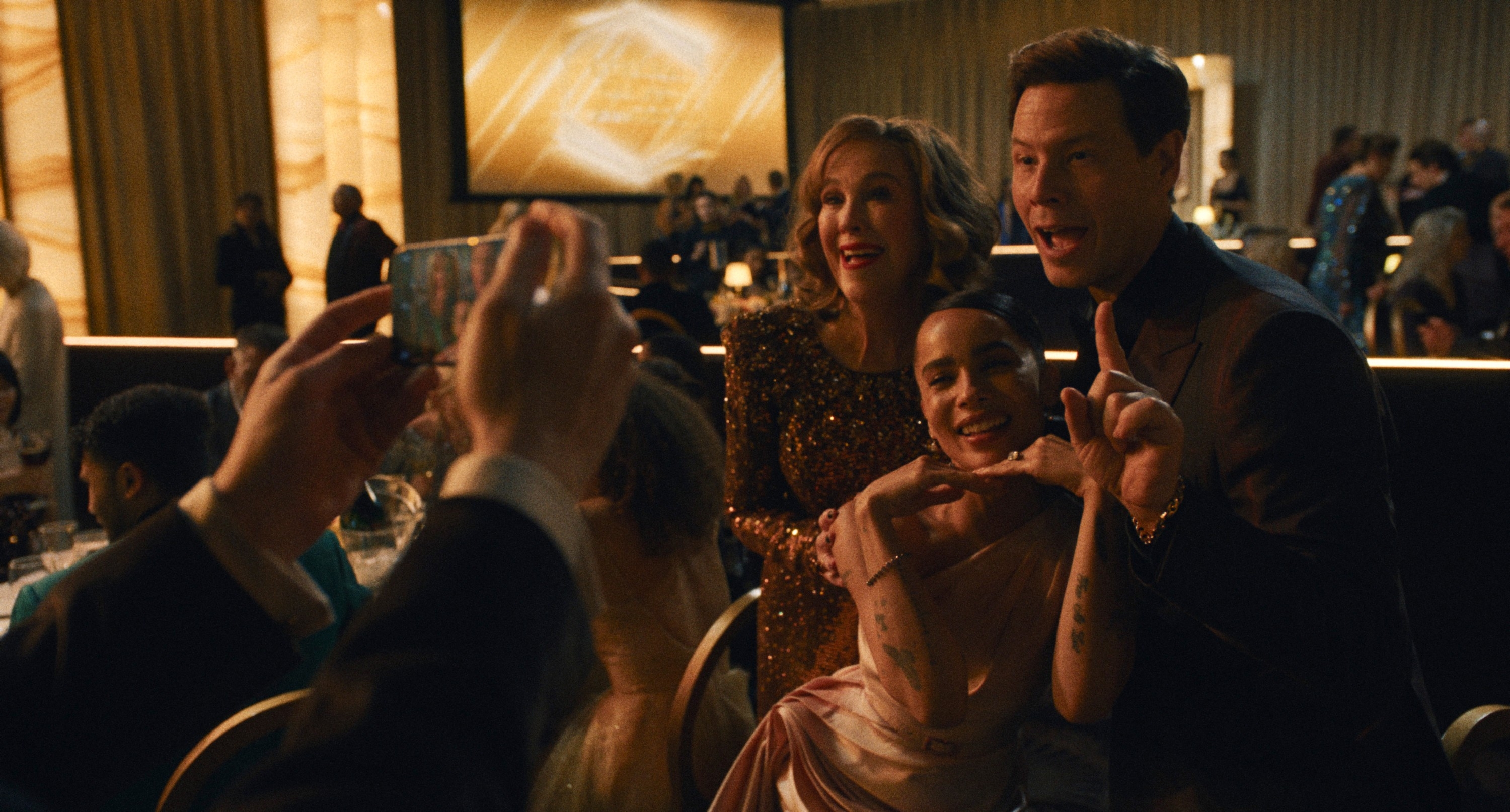 Three radical   airs  for a photograph  astatine  a ceremonial  event, 2  successful  elegant attire and 1  successful  a tuxedo. People and a ample  surface  are disposable   successful  the background