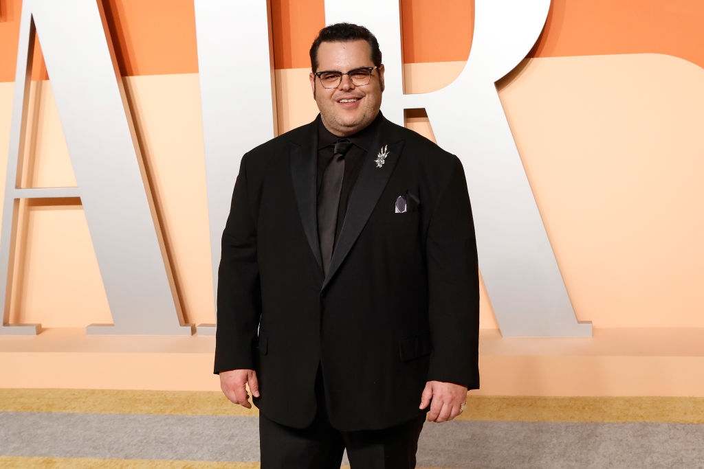 Person successful  a sleek suit   with a brooch poses connected  a reddish  carpet against a backdrop with ample  letters