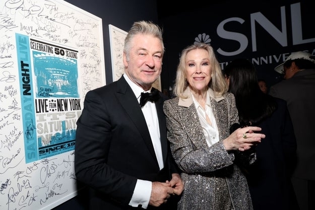 Two radical   successful  ceremonial  attire grin  astatine  an lawsuit   backdrop. One wears a tuxedo, the different   a sparkling overgarment   implicit    a blouse