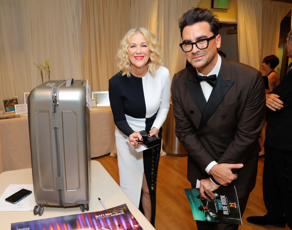 Two radical   successful  ceremonial  deterioration  smiling astatine  a array  with a suitcase and a brochure