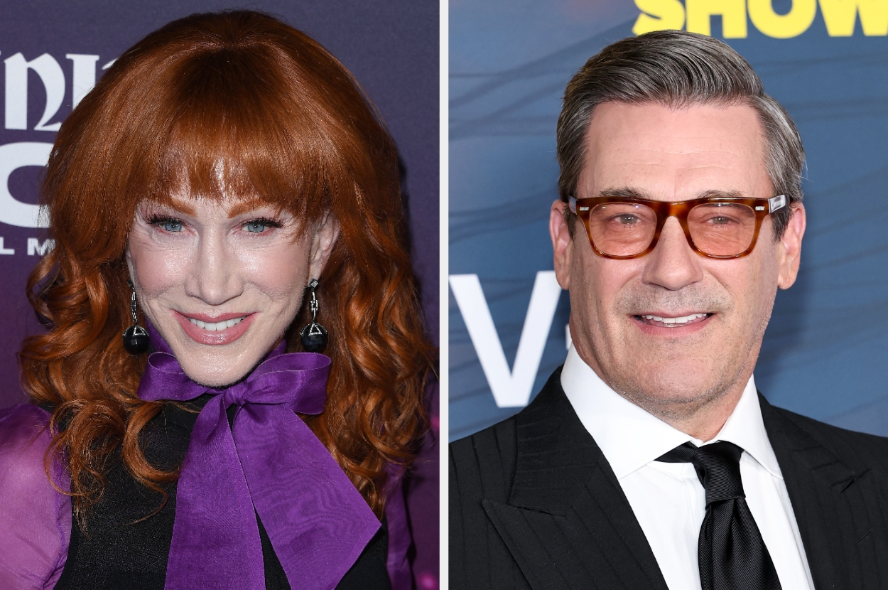 Two people at a media event. Left: Woman with wavy hair, wearing a bow-tied top. Right: Man with glasses, in a suit and tie. Both smiling at the camera