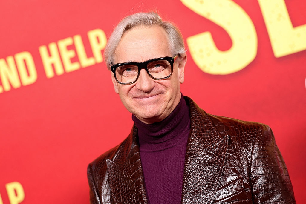 Person wearing a textured suit   overgarment   and turtleneck, posing connected  a reddish  carpet with a agleam  inheritance  featuring ample  text