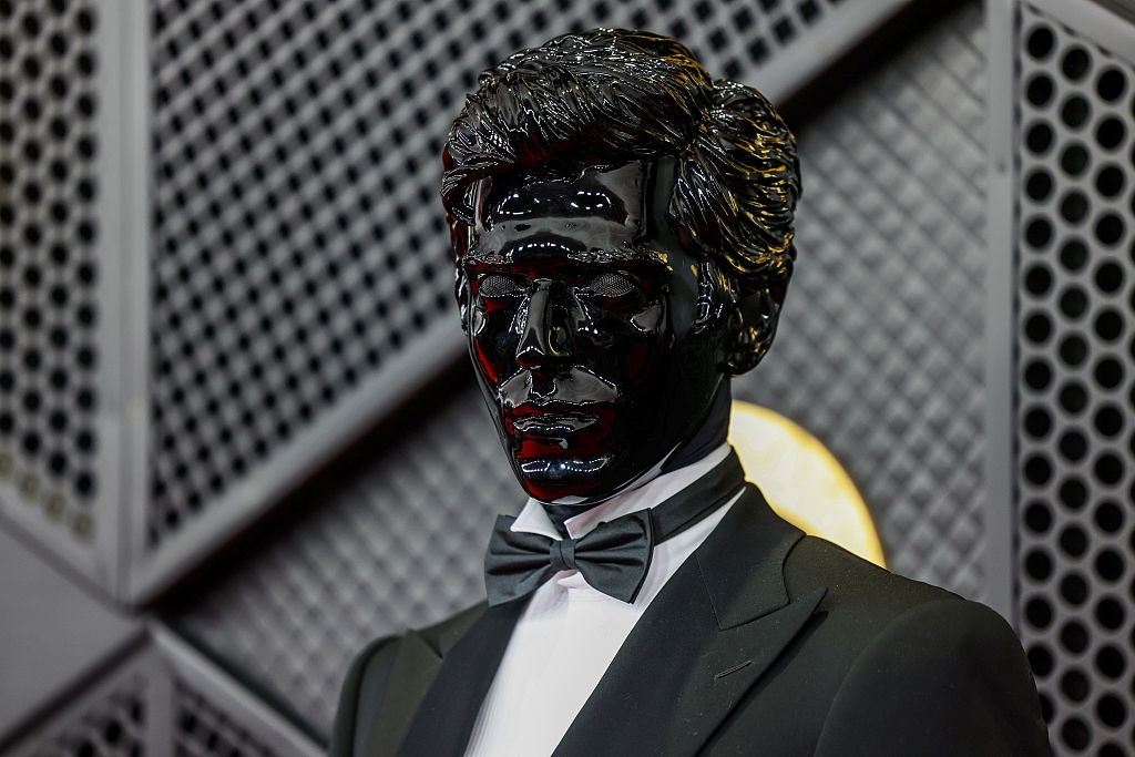 Person successful  a glossy, face-covering sculpture suit   with ceremonial  attire, including a bow tie, astatine  a personage  event