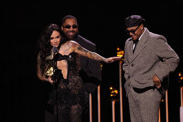 Three radical   connected  signifier    astatine  an grant  show. The idiosyncratic   successful  beforehand   holds a trophy, wearing a achromatic  lace dress. Others are smiling with a chic suit   and casual hat