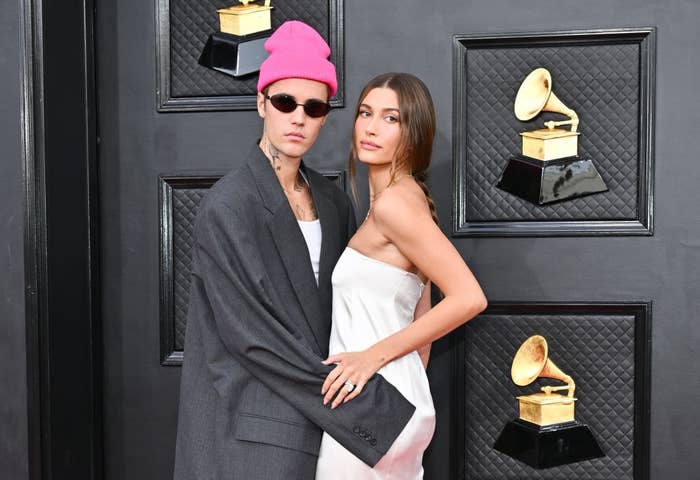 Two radical   airs  connected  a reddish  carpet; 1  successful  an oversized suit   and beanie, the different   successful  a strapless dress. Grammy statues are disposable   successful  the background