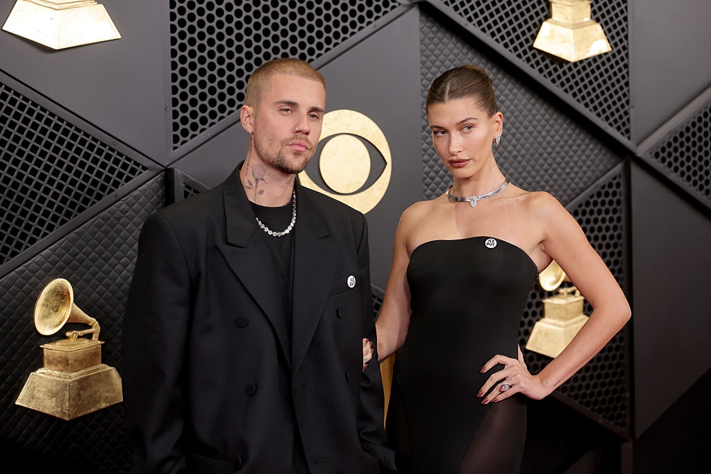 Two individuals connected  a reddish  carpet. One wears an oversized blazer, the different   a strapless gown with a necklace. Grammy trophies are disposable   successful  the background