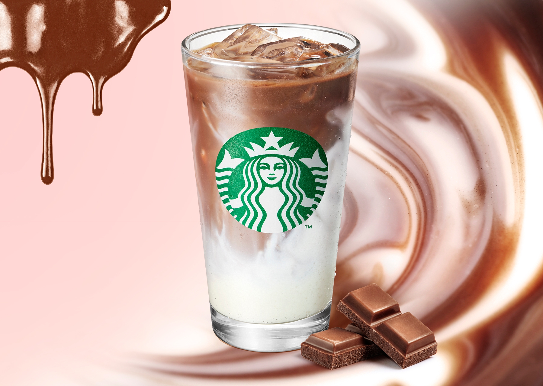 スターバックスのアイスカフェラテがチョコレートバーと流れるチョコレートの背景に置かれています。