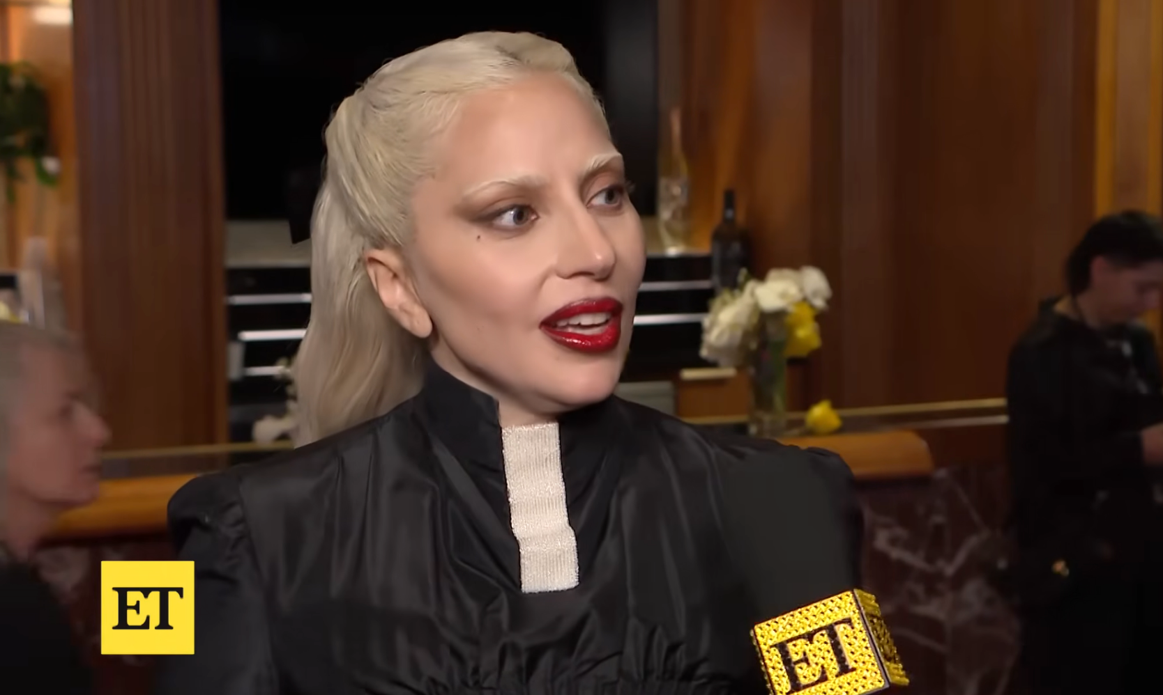 Person successful  elegant high-collared formal  giving an interview, holding a microphone with "ET" logo successful  a ceremonial  setting