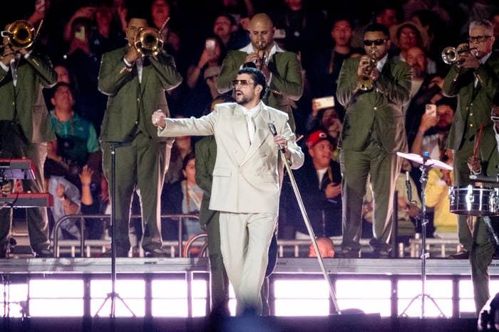 A performer successful  a beige suit   sings connected  signifier    with a brass set  successful  matching suits playing down  them