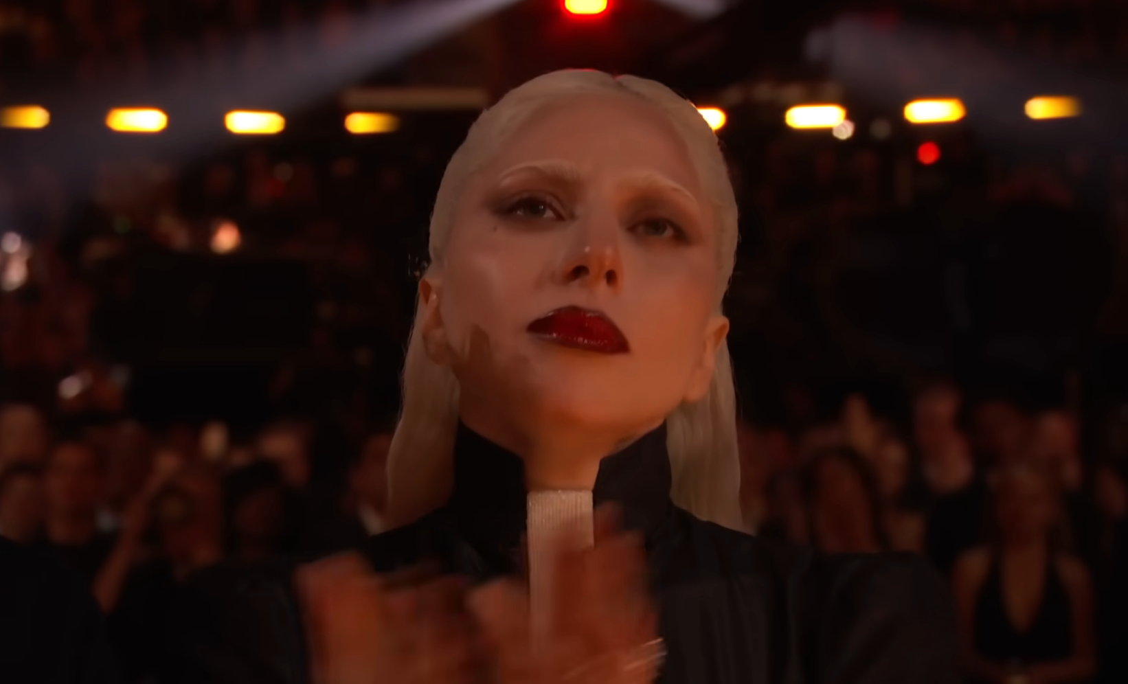 A idiosyncratic   with slicked-back hairsbreadth  and acheronian  lipstick claps successful  an assemblage  setting