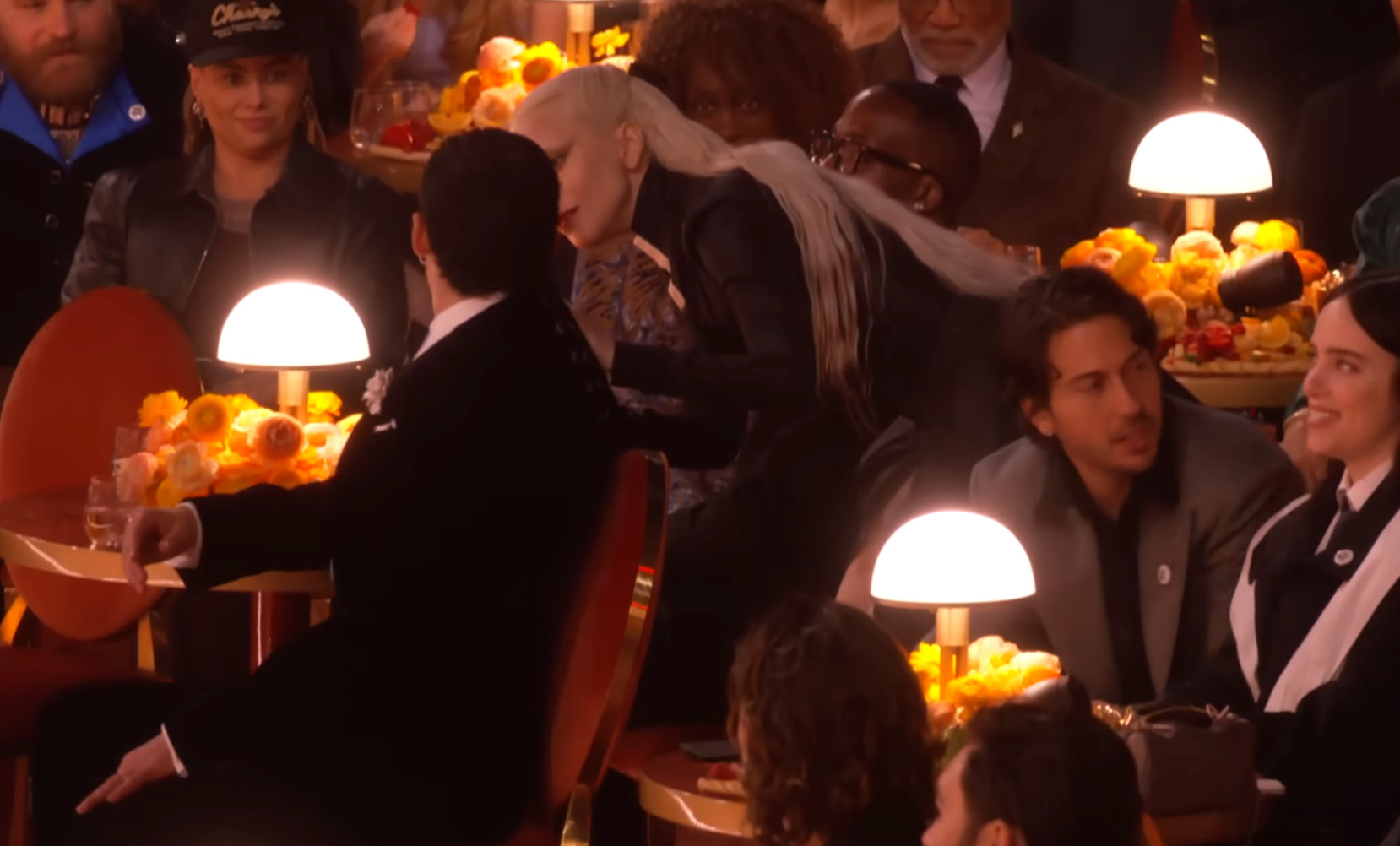 A radical  of radical   seated astatine  an lawsuit   with array  lamps and flowers, 1  idiosyncratic   with agelong  hairsbreadth  appears to beryllium  speaking to different  person