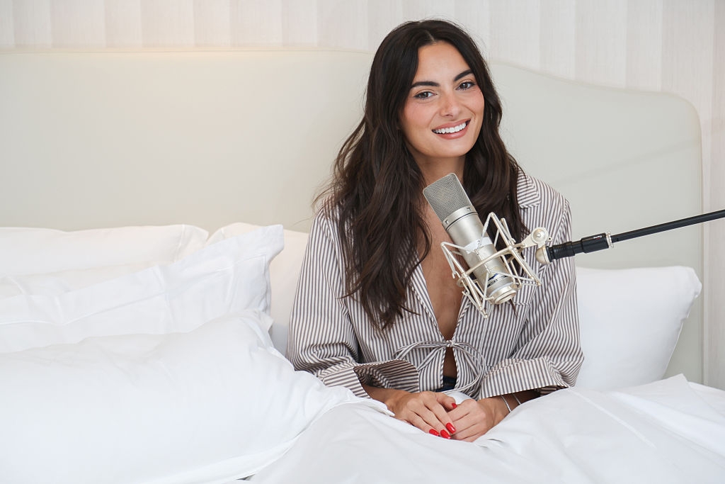 A idiosyncratic   smiles portion    sitting successful  bed, wearing a striped robe, successful  beforehand   of a microphone, perchance  signaling  a podcast oregon  interview