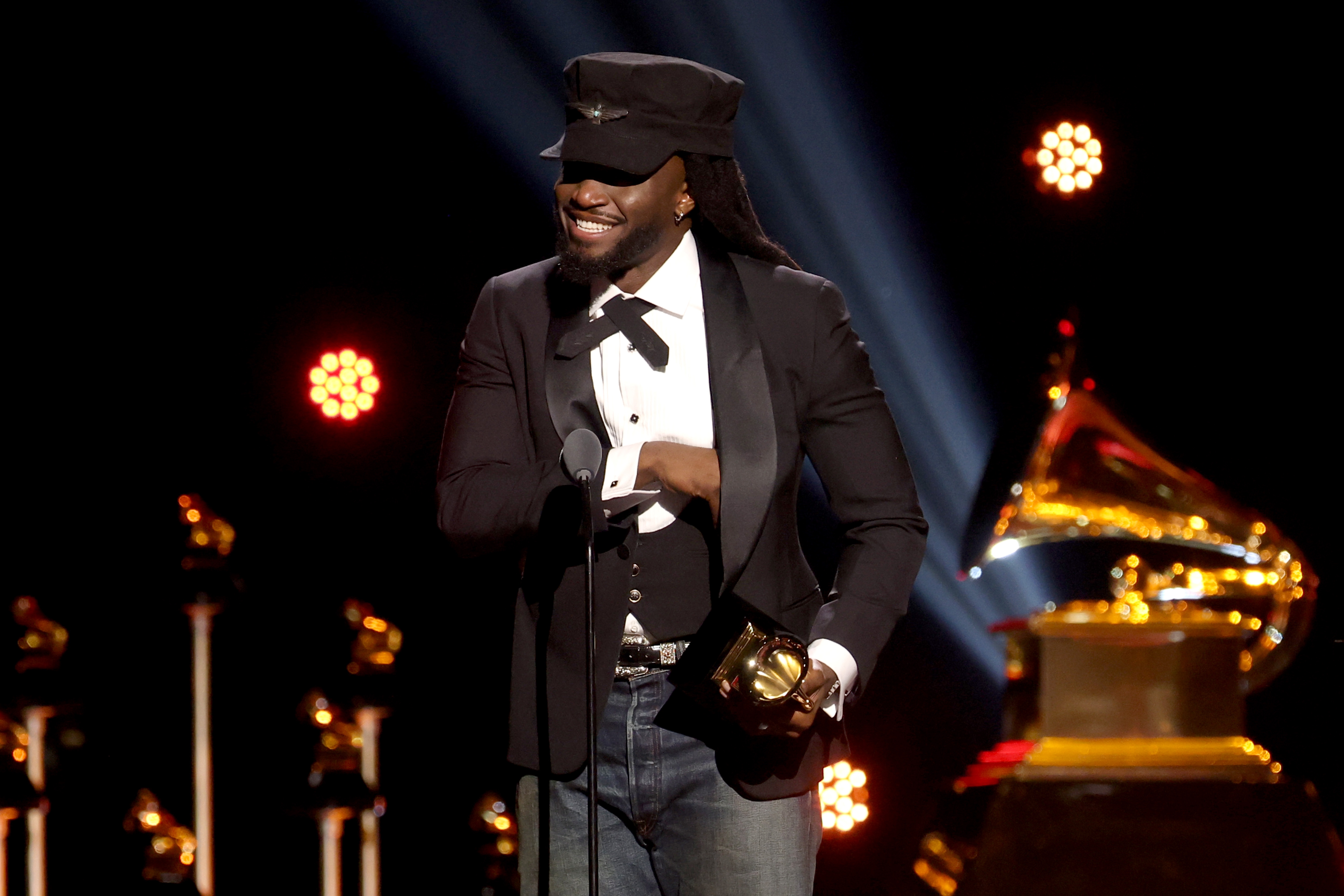 Person successful  ceremonial  attire with a military-style chapeau  holding a Grammy grant  connected  signifier    with a ample  Grammy trophy disposable   successful  the background