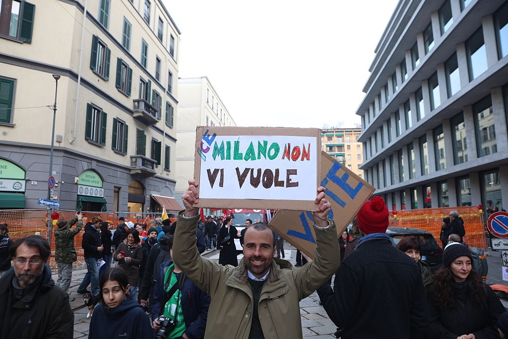 Person som holder et skilt i en bygate der det står 