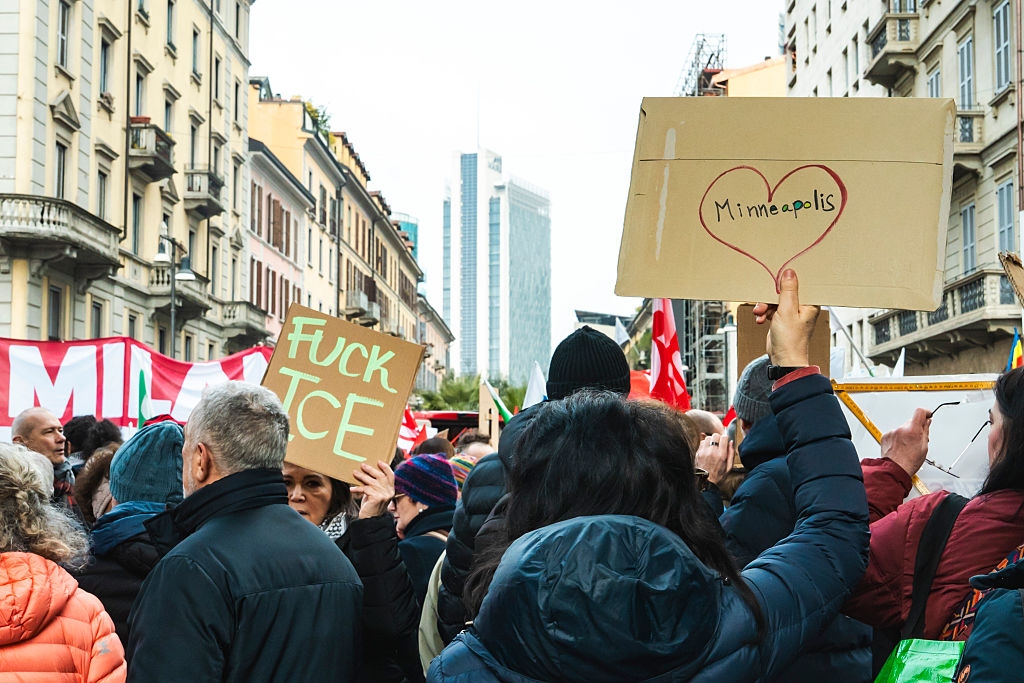Folk samlet seg ved en gateprotest med skilt, inkludert et som sier 