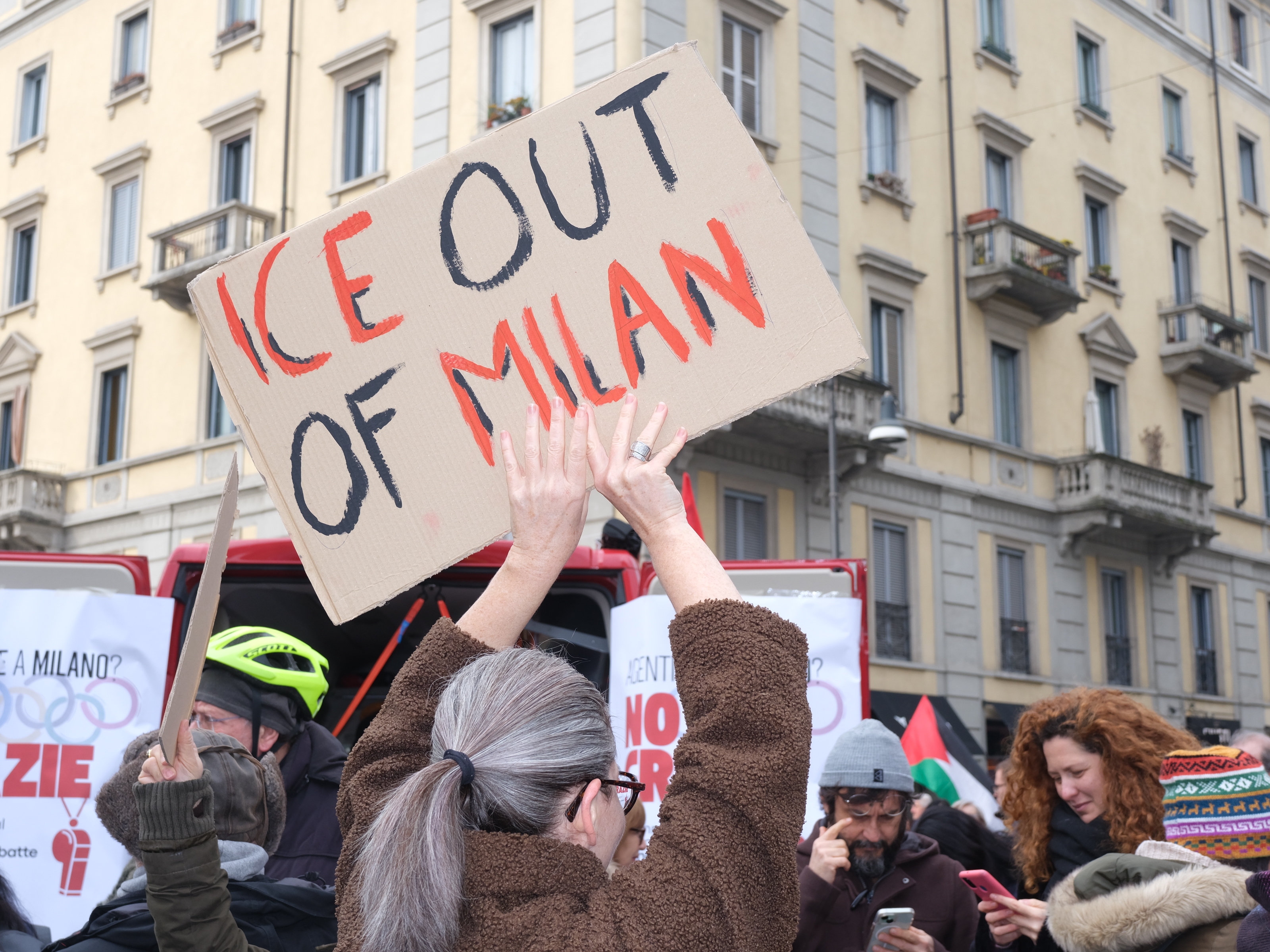 Demonstranter i en by holder skilt, hvor en tydelig leser «ICE Out of Milan».