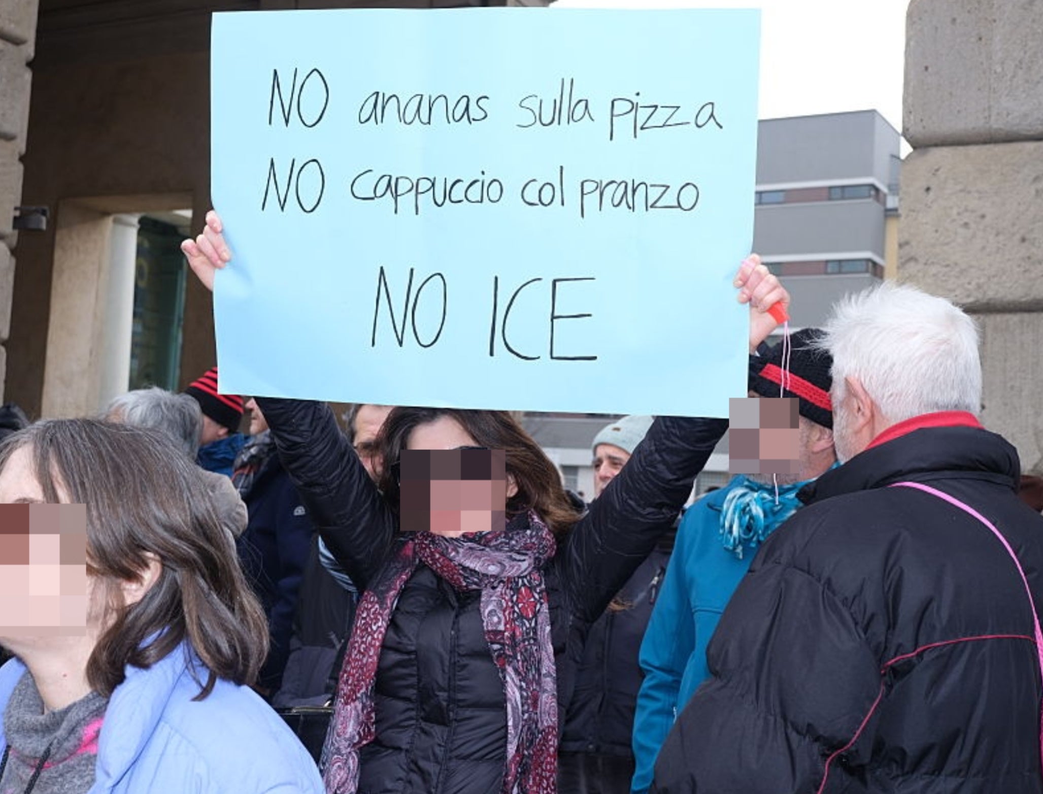 En gruppe mennesker på en protest, med en kvinne som holder et skilt som leser: 