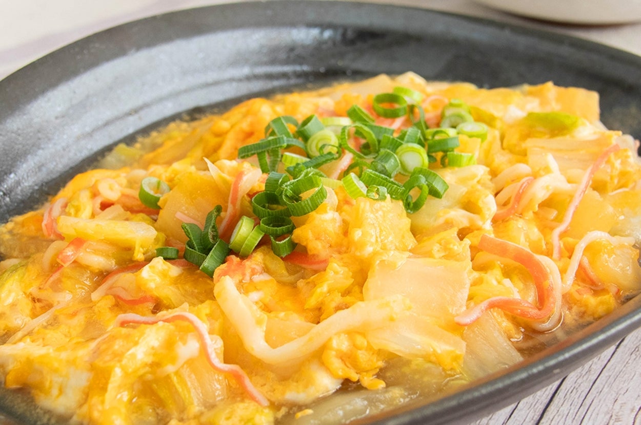 白菜と卵とカニカマの中華煮が黒い皿に盛られています。