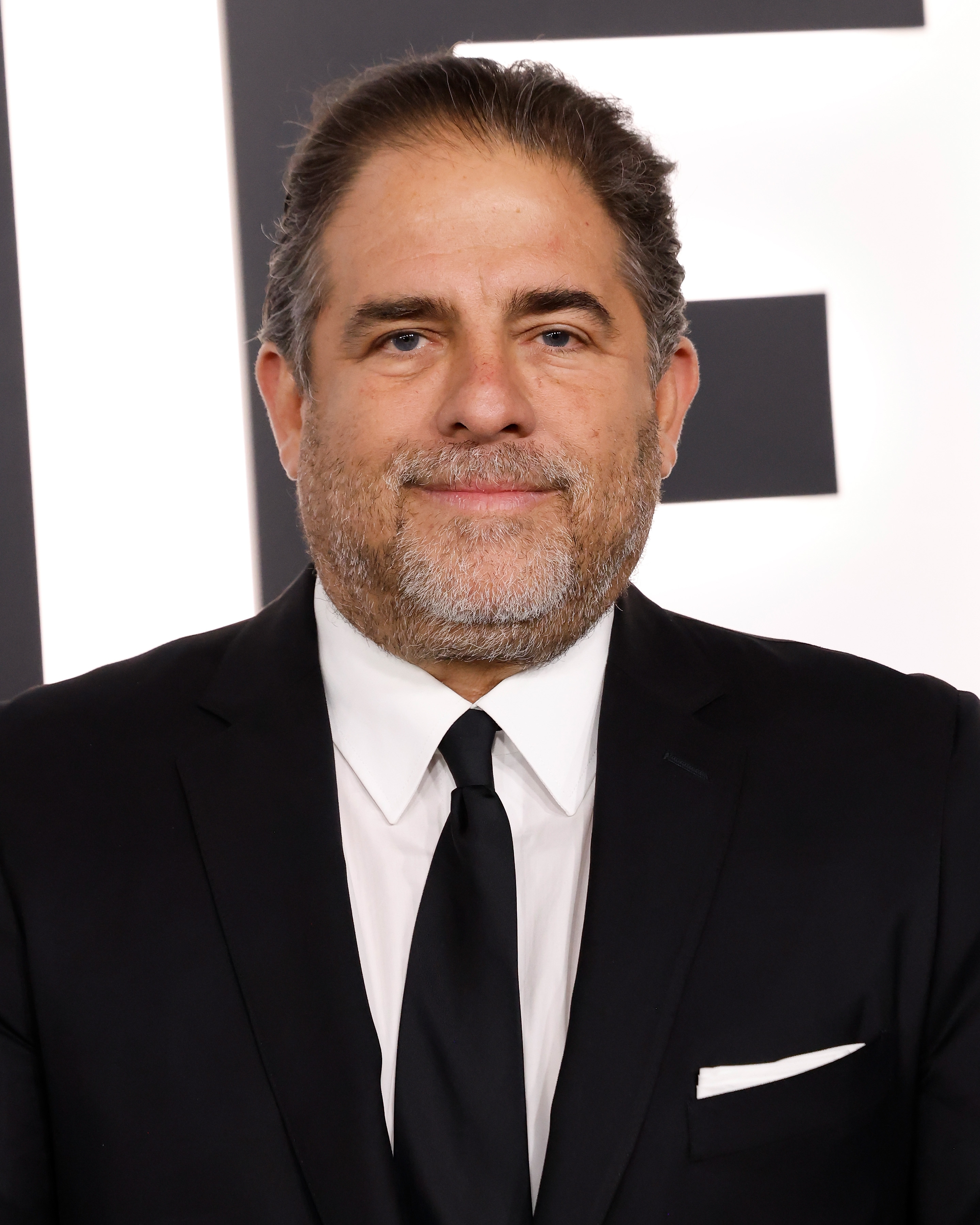 Brett Ratner smiler i dress og slips på et arrangement