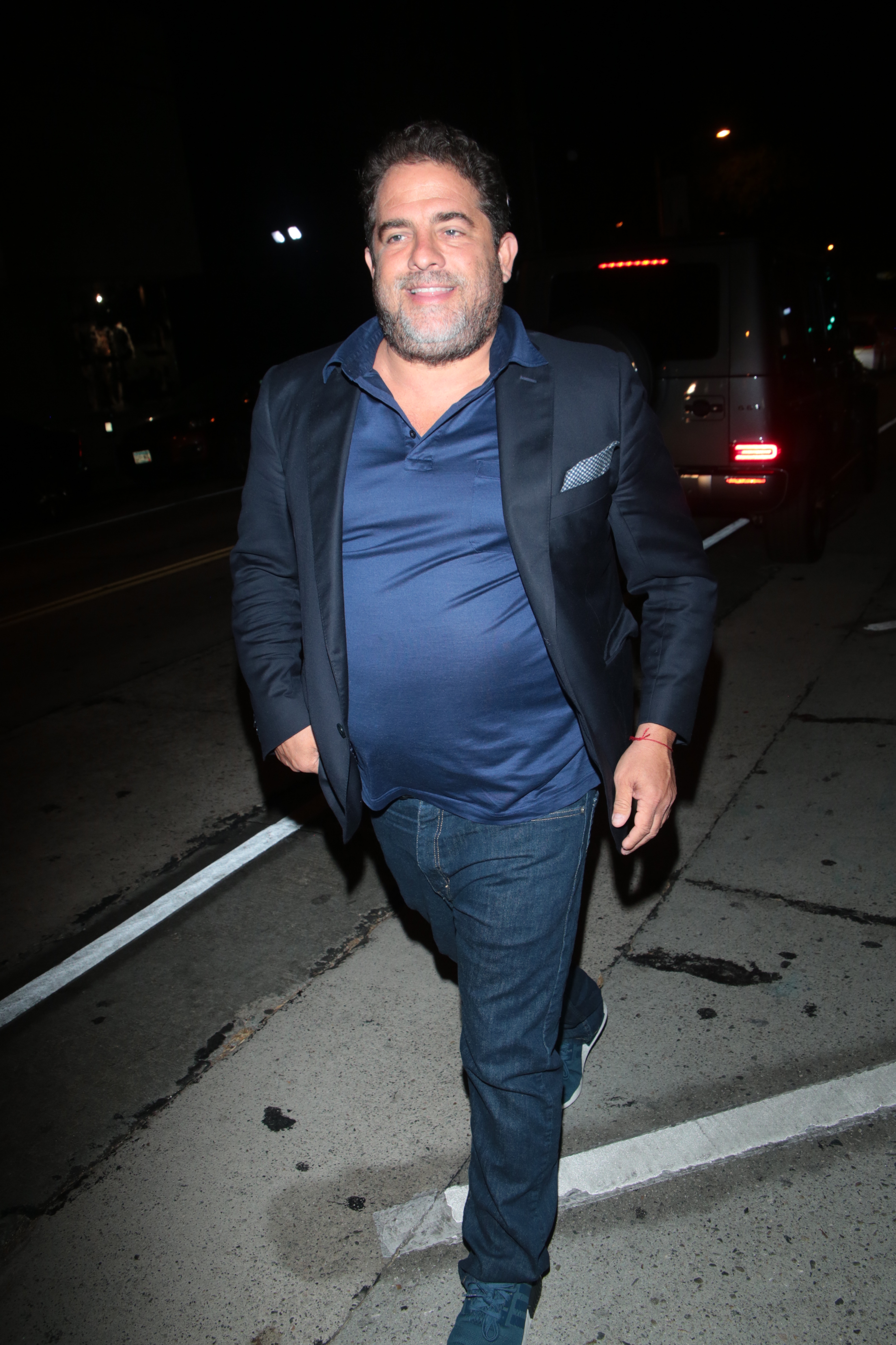 Brett Ratner successful  a casual suit   walks confidently connected  a metropolis  thoroughfare  astatine  night