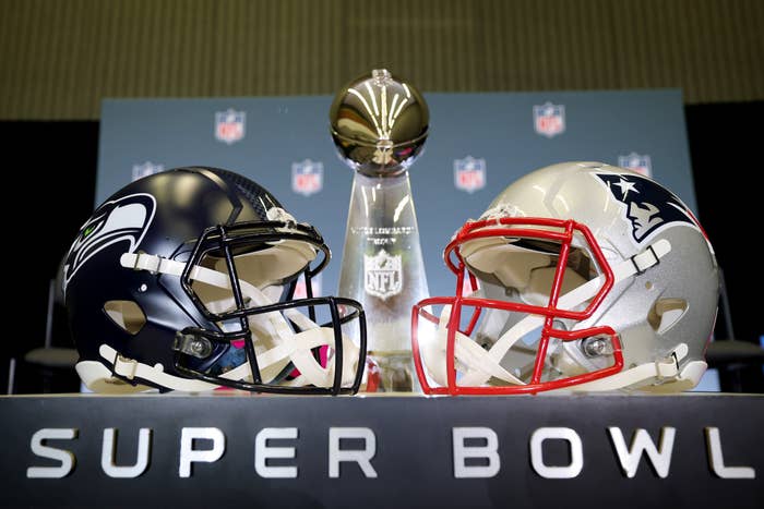 Seattle Seahawks and New England Patriots helmets displayed with the Super Bowl trophy in the background