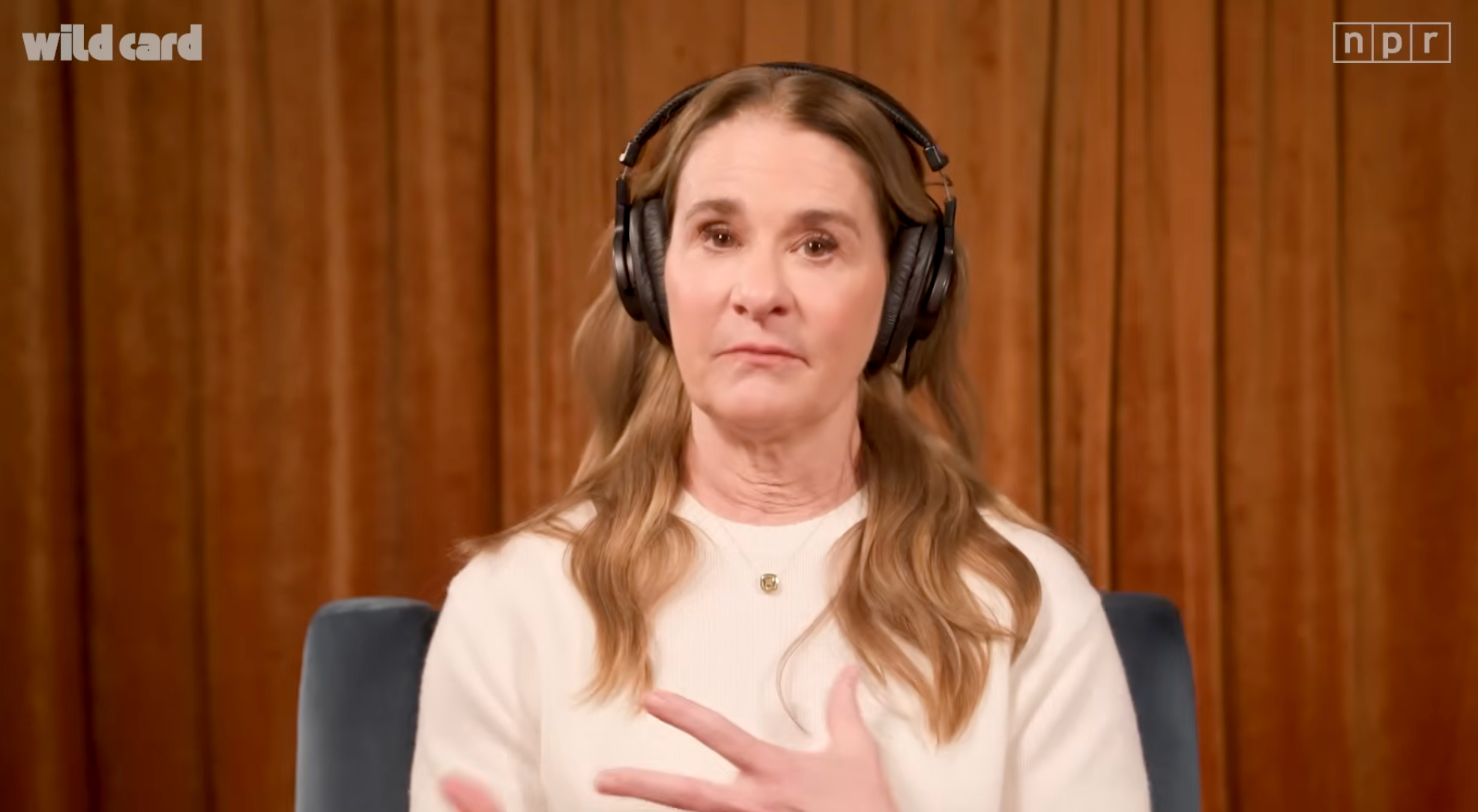 Person med hodetelefoner, sittende, snakker foran et trebakteppe, vises på et NPR-show