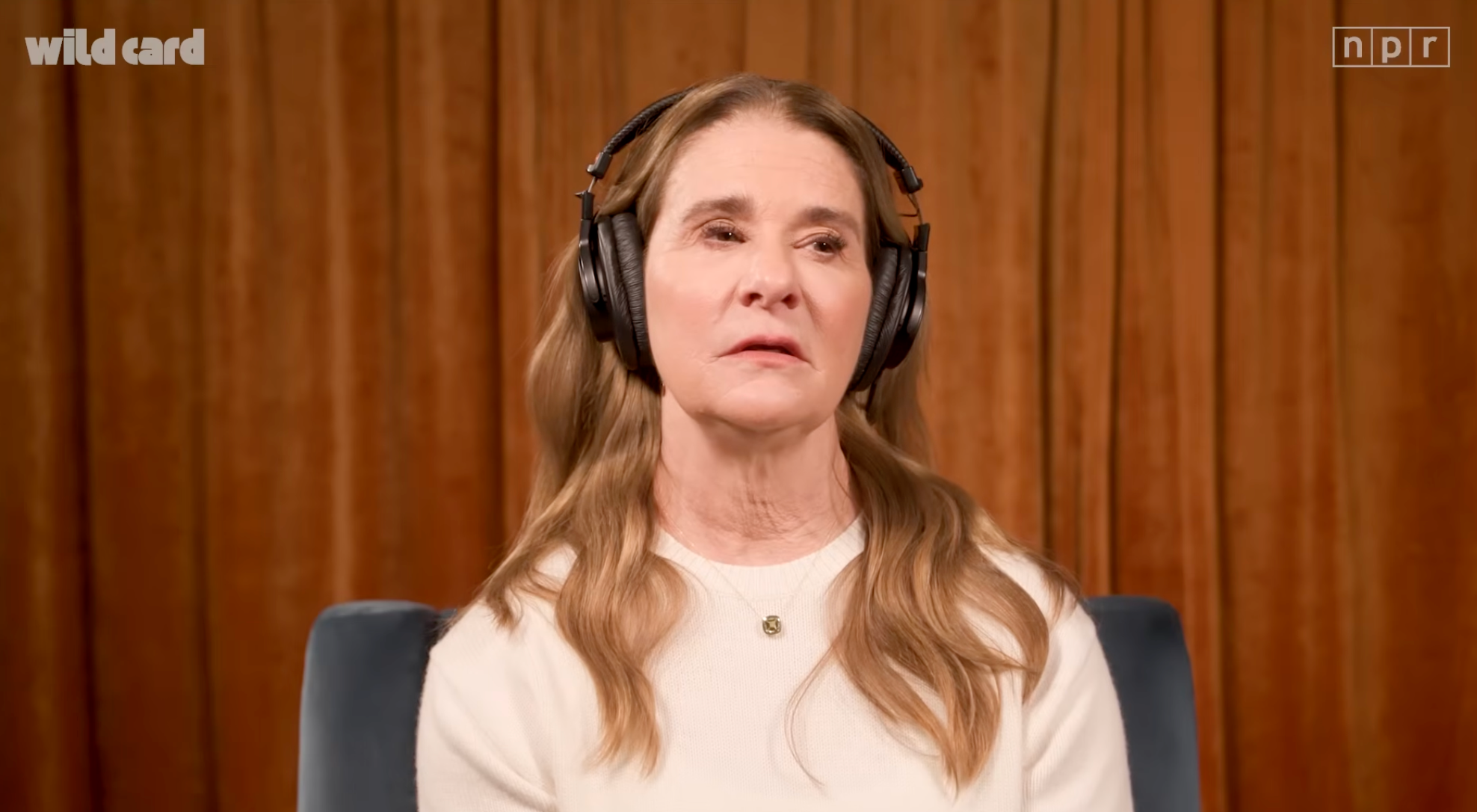 Person som bruker hodetelefoner, sitter foran et gardin, blir sannsynligvis intervjuet for en podcast eller radiosegment