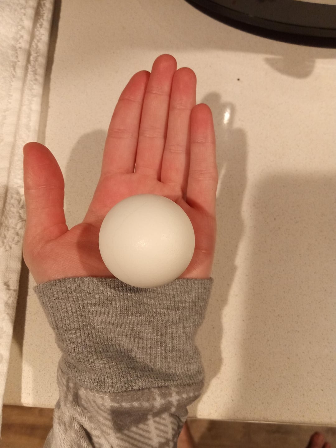 Hand holding a perfectly   round, creaseless  achromatic  object, perchance  a shot  oregon  a ample  marble