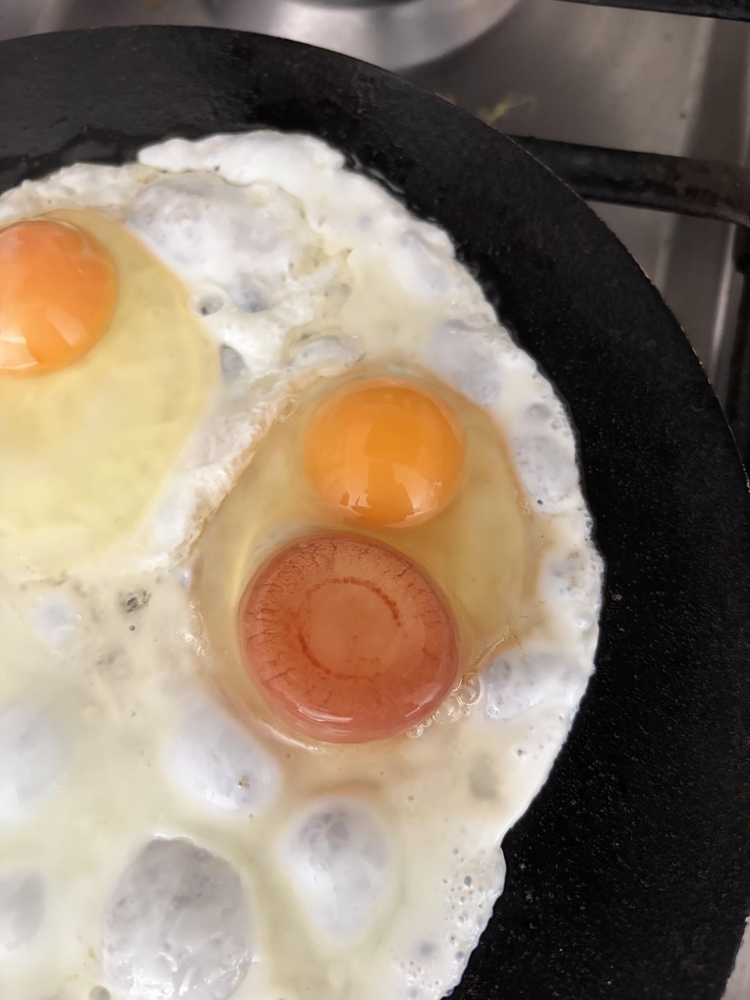 Frying cookware  with 3  eggs being cooked sunny-side up