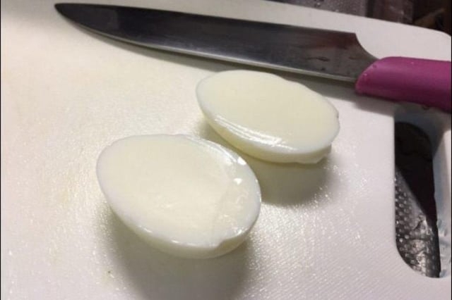 A weapon  and 2  hard-boiled eggs chopped  successful  fractional  connected  a achromatic  cutting board