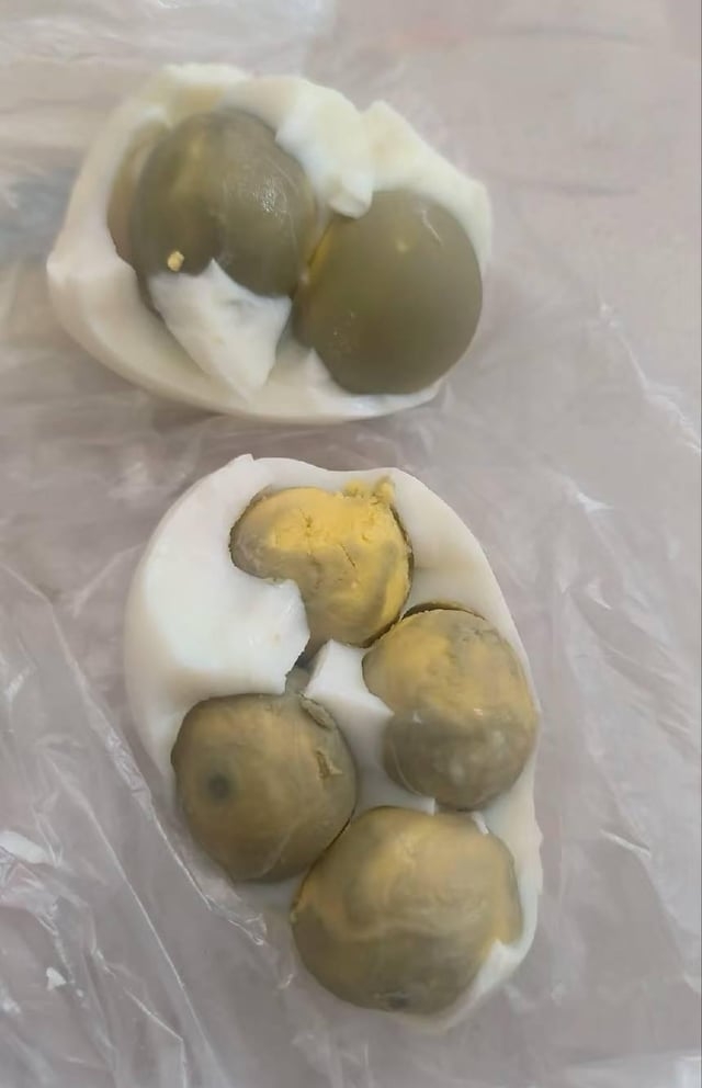 Two halves of a boiled ovum  each   incorporate  aggregate  tiny  greenish  olives inserted wherever  the yolks would typically be