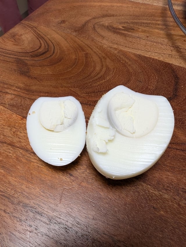 Two hard-boiled eggs with the yolks missing, placed connected  a woody  surface
