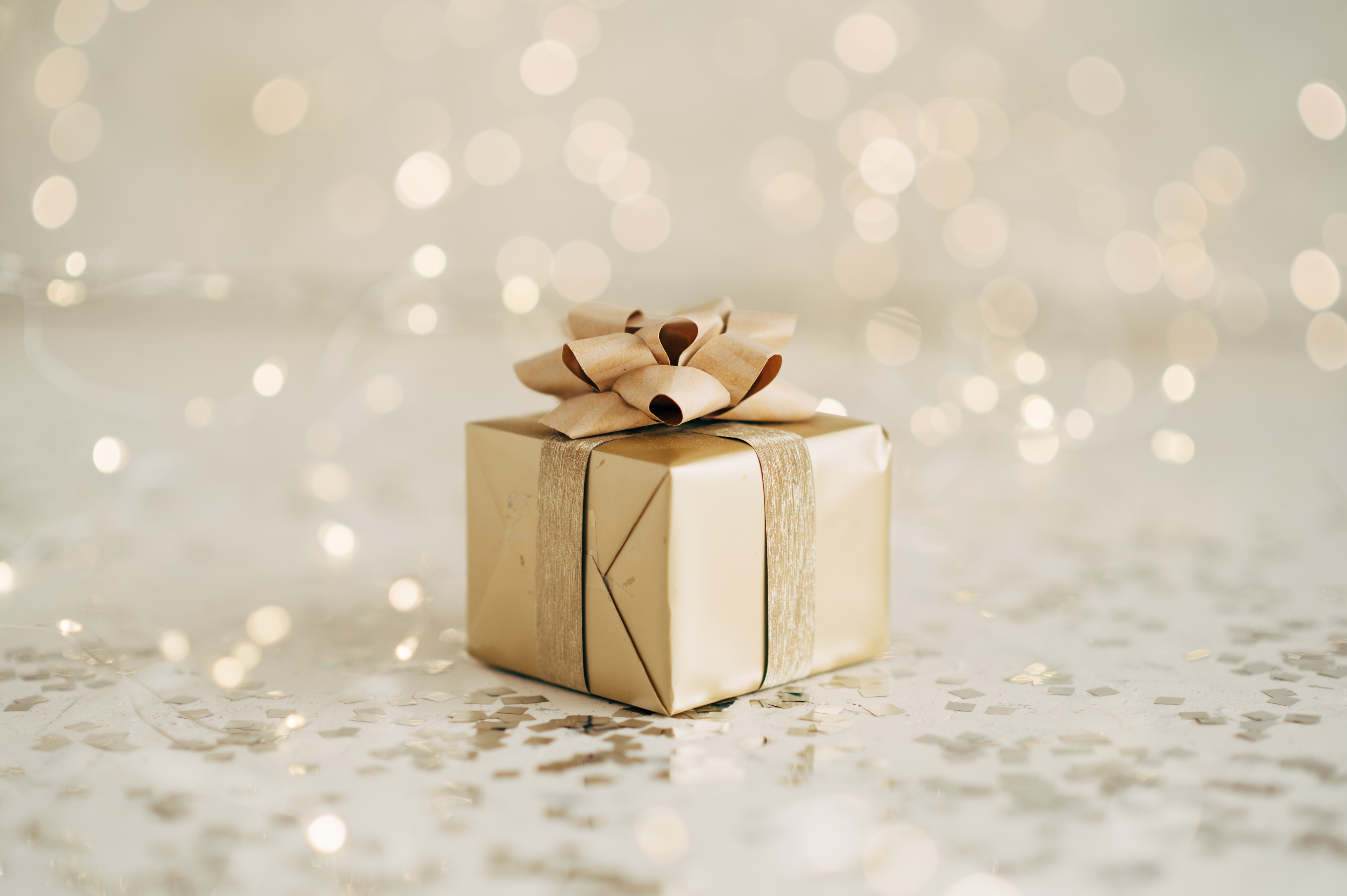 キラキラした背景に置かれたリボン付きのギフトボックス。