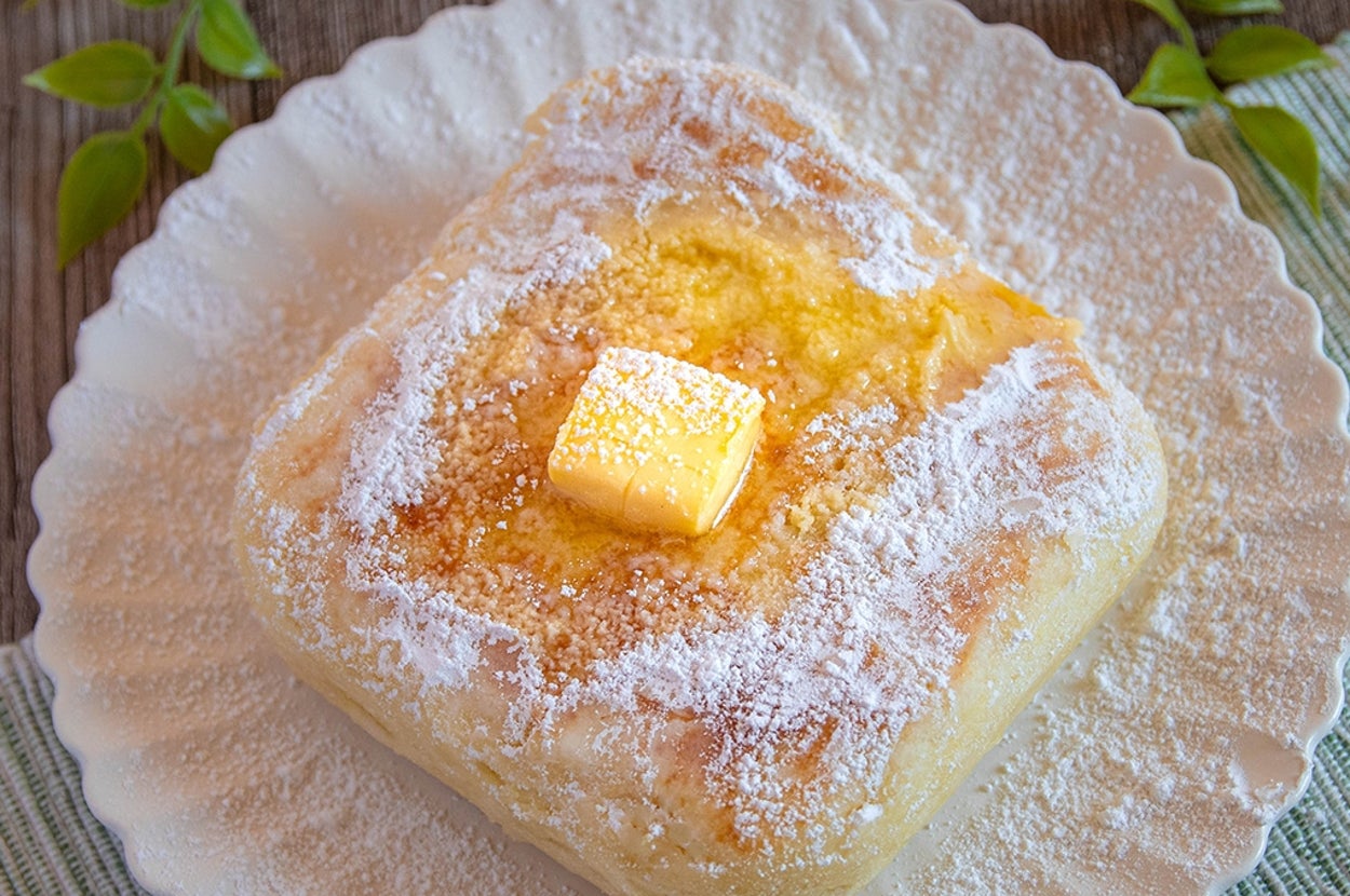 皿にのったパンの上にバターがのっている。周囲に緑の葉の飾りがある。